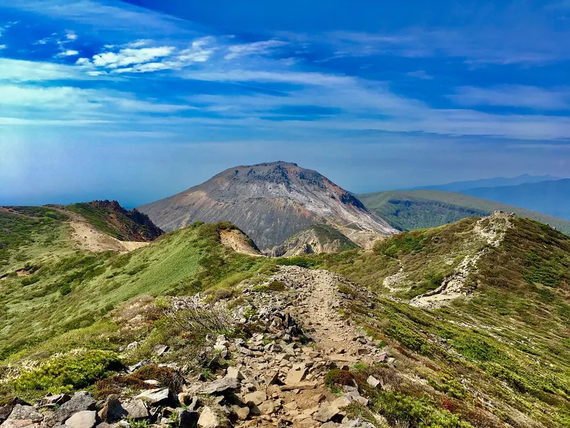 那須連山の稜線と登山道が見える高原の風景